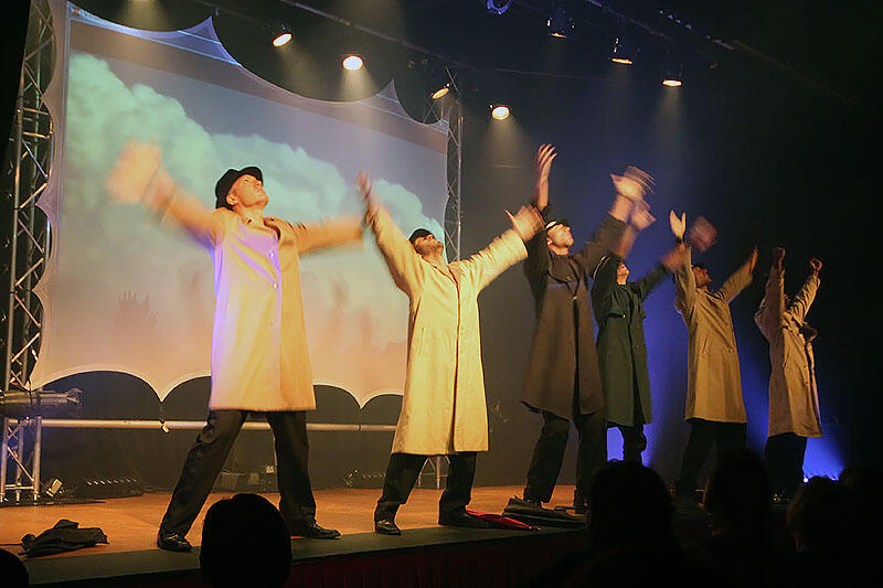 Canadian Storm Male Revue troupe on stage performing choreography together with arms raised high