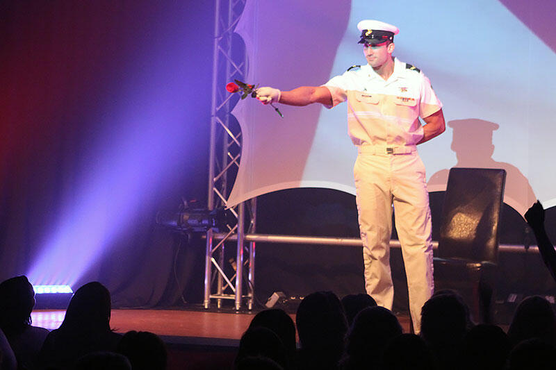 Canadian Storm Male Revue - Tom Rooney on stage Performer and author Thomas (Tom) Rooney of Canadian Storm on stage in his Naval officer costume holding a rose and pointing at the audience