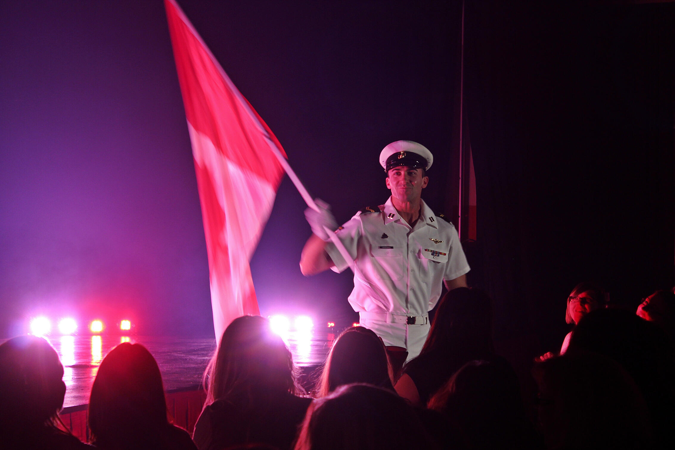 Canadian Storm Male Revue - live performance photo Performer and author Thomas (Tom) Rooney waving a Canadian flag on stage during a Canadian Storm live show